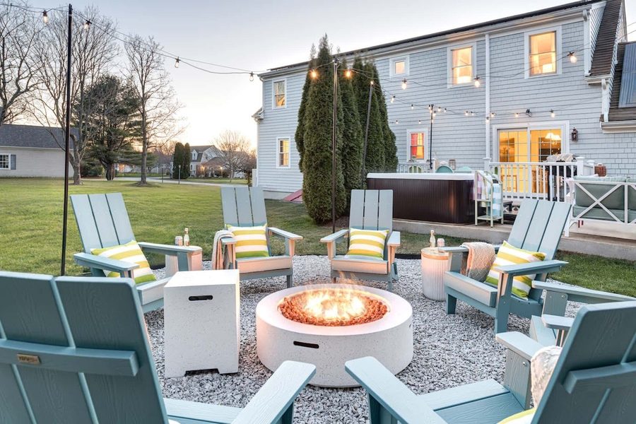 Backyard at dusk with fire pit, hot tub, and string lights