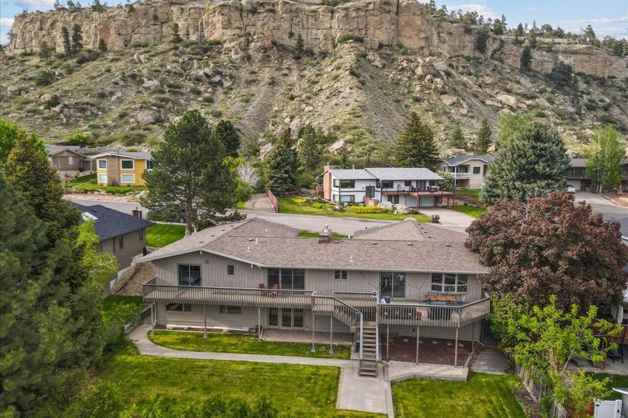 Aerial view of a large home beneath rimrock cliffs